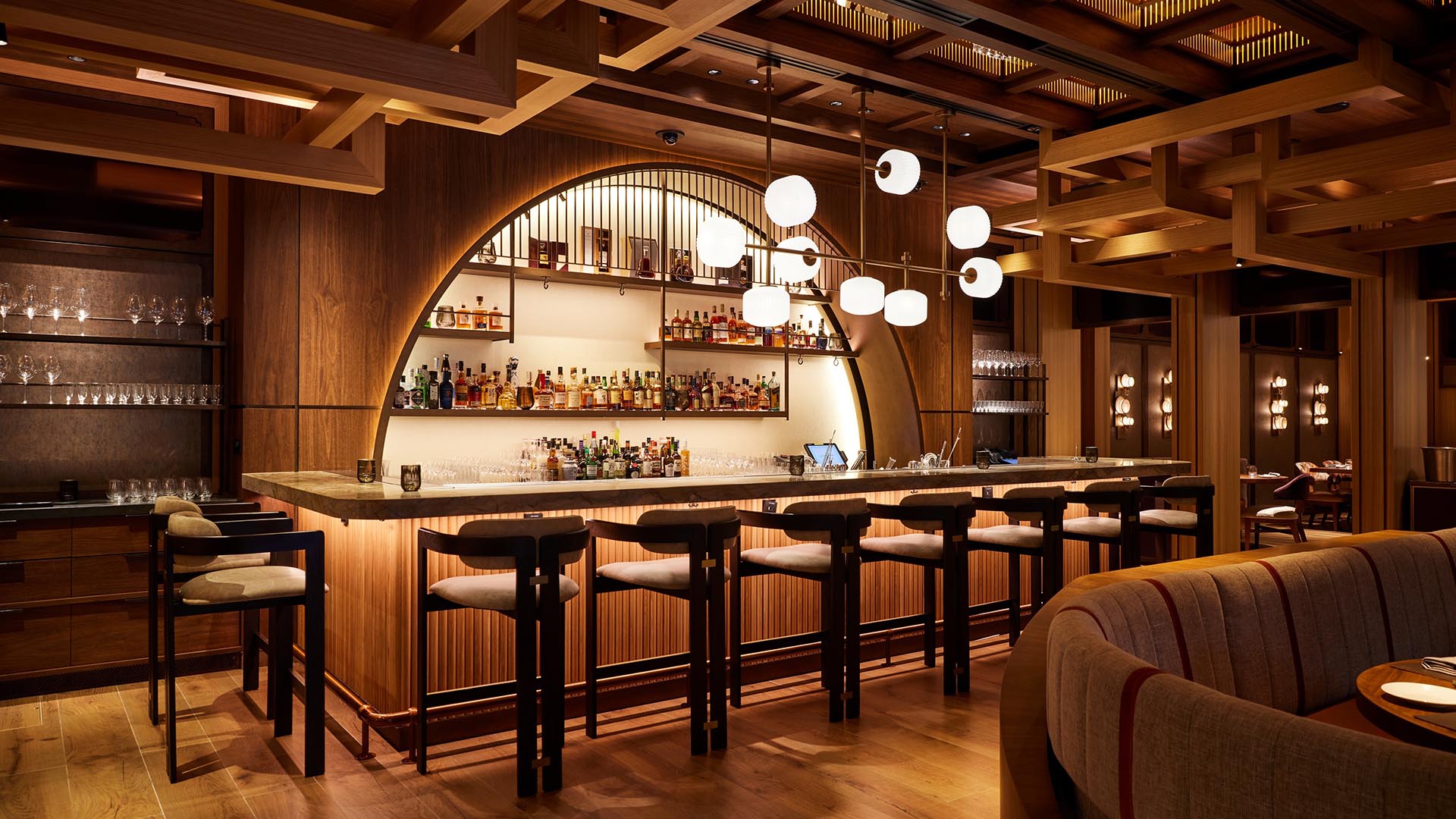 Area bar berperabot lengkap dengan meja tinggi, kursi, dan minuman beralkohol di Wakuda Restaurant & Bar, sebuah restoran layak Instagram di Singapura