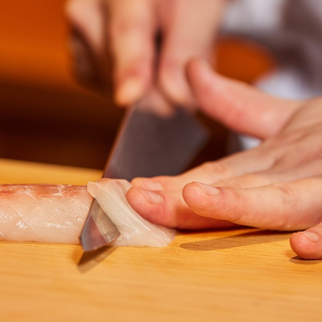 Chef menyiapkan seiris sashimi di sebuah restoran omakase di Singapura