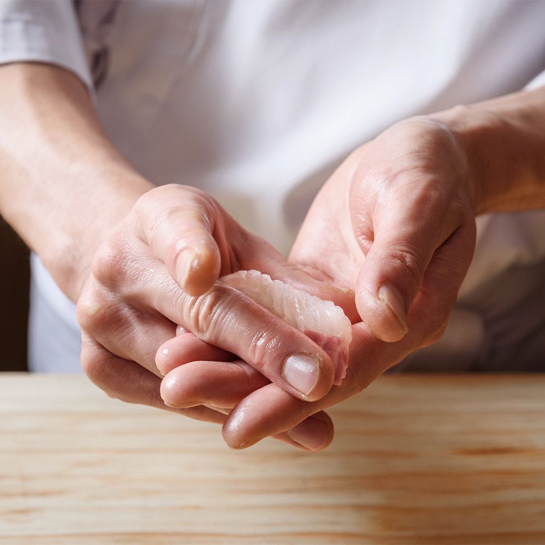 Chef menyiapkan sushi nigiri omakase dengan tangan bersih