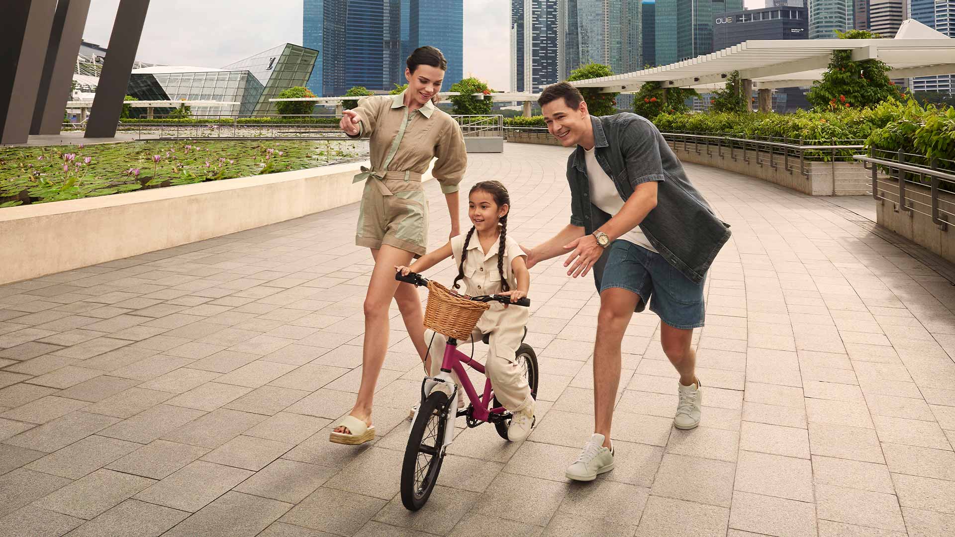 Keluarga beranggotakan tiga orang dengan anak yang mengendarai sepeda untuk merayakan aktivitas Hari Ibu