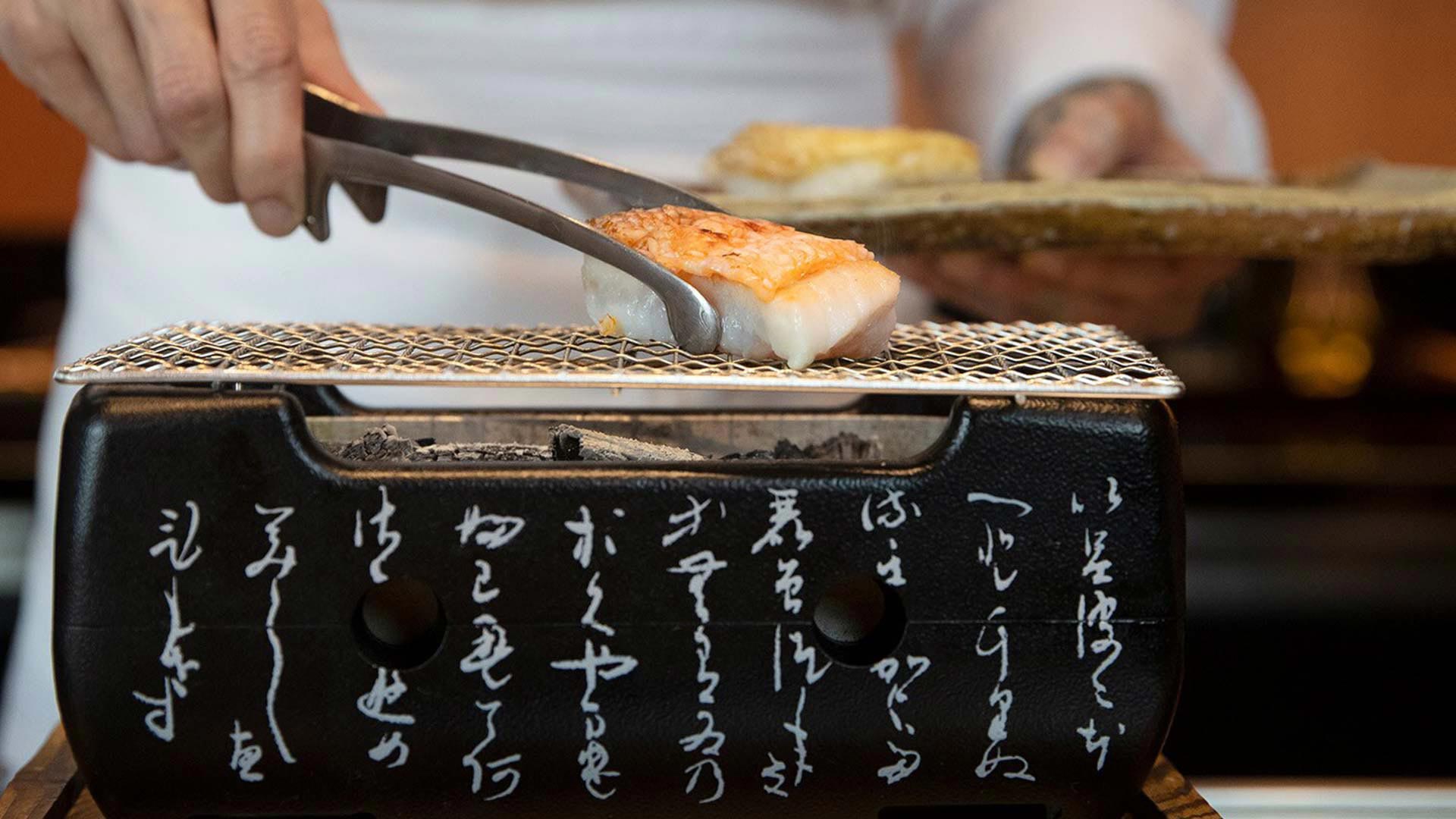 Chef membakar ikan di atas arang di Waku Ghin, restoran untuk menggelar acara bersantap privat